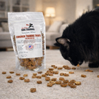 Whole chicken dog training treats made in the USA, single-ingredient dehydrated white and dark chicken meat pieces in an 8 oz resealable bag on an indoor floor with a cat